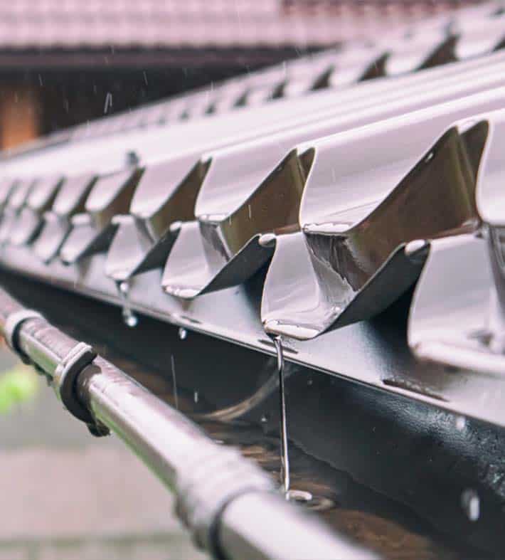 Close-up of a rain gutter system with rainwater flowing through.