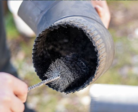 Handheld wire brush cleans a chimney flue during chimney repair in NJ