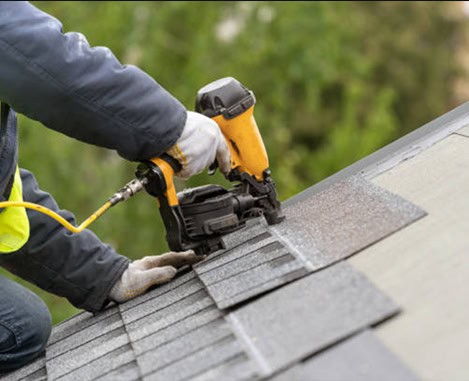 Roofer performing roof replacement on a sloped asphalt shingle roof.