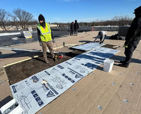 Roof replacement underlayment being installed on a flat New Jersey roof by workers