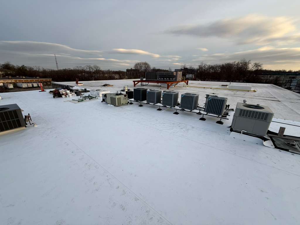 Snow-covered flat roof with row of rooftop HVAC condensers on Clifton NJ building