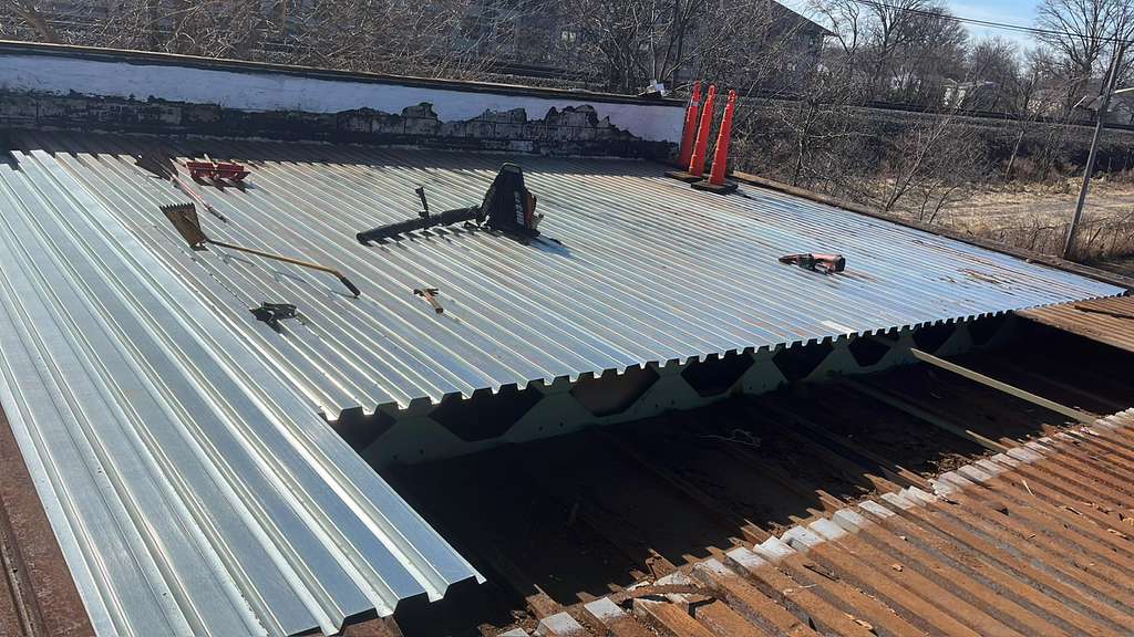 Metal roof panels being installed on a residential roof during roof replacement in New Jersey