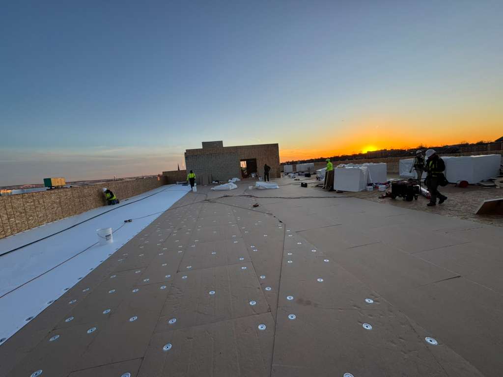 BlueSky roofing crew performing roof replacement on a flat New Jersey roof at sunset