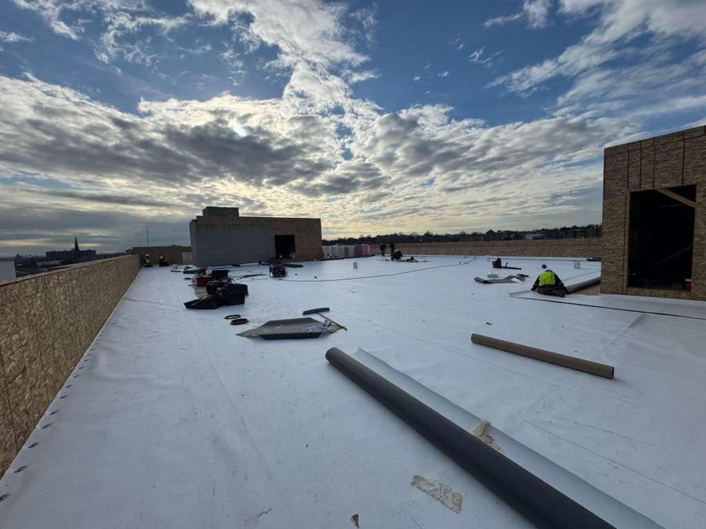 BlueSky crew on a flat white roof with scattered materials performing roof replacement in New Jersey