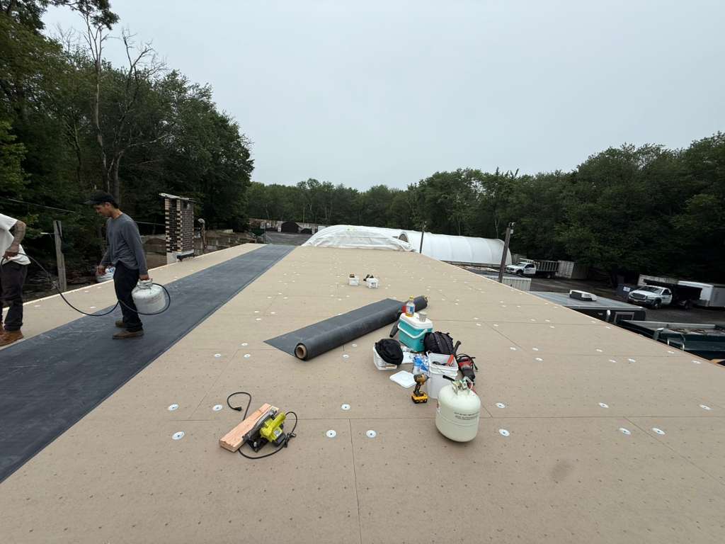 BlueSky roofing crew installing roof membrane on a flat roof during roof replacement in New Jersey