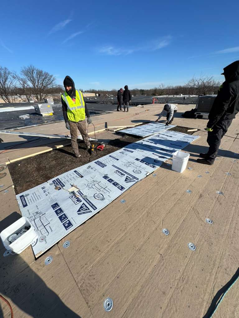 BlueSky roofing crew laying underlayment on a flat roof for roof replacement in New Jersey.