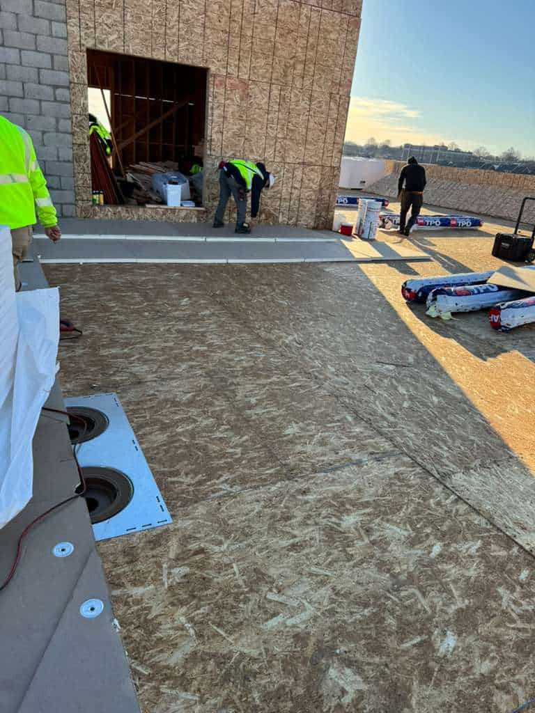Roof replacement underway on a flat roof in New Jersey; workers in hi-vis.
