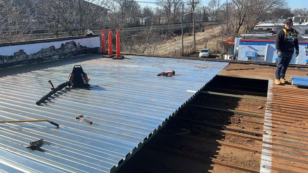 BlueSky roofing crew performing roof replacement on a partially completed metal-panel roof in NJ
