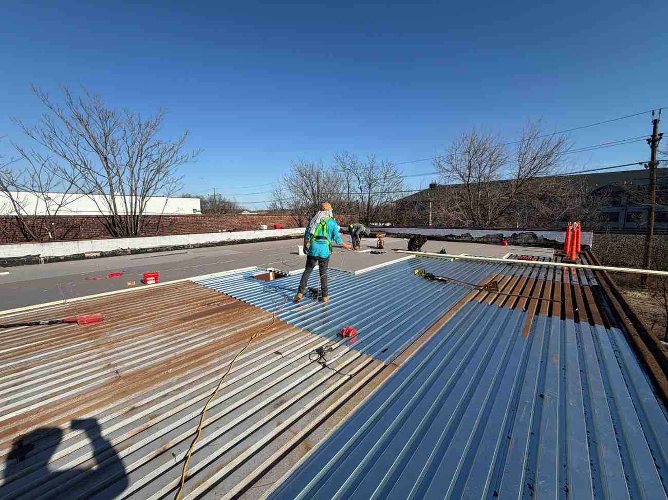 BlueSky roofing crew installing blue metal roof panels during roof replacement in New Jersey