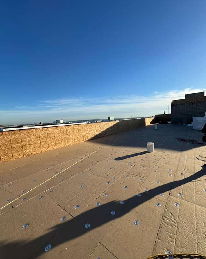 Flat roof replacement prep on Clifton NJ rooftop with tan underlayment and screws.