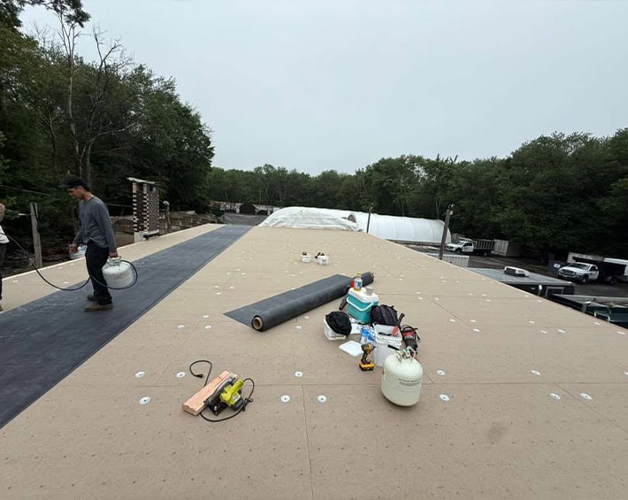 BlueSky Roofing crew applying underlayment on a flat roof in New Jersey for roof replacement