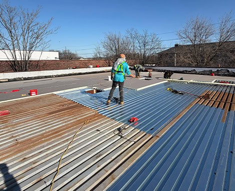 BlueSky Roofing & Siding crew installing metal roof panels during roof replacement on a flat rooftop in New Jersey