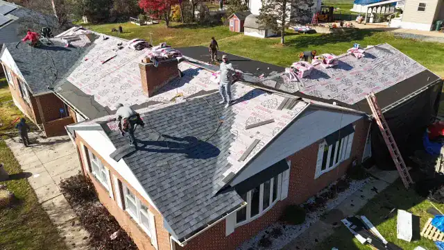 Professional roof replacement project in progress on a residential brick home by BlueSky Roofing & Siding