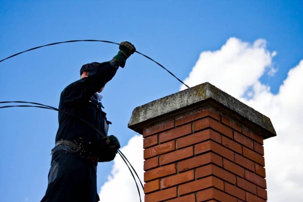 BlueSky roofing crew guiding cables over a brick chimney in New Jersey