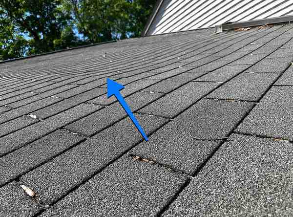 Close-up of damaged asphalt shingle with missing granules on roof for roof leak repair in New Jersey