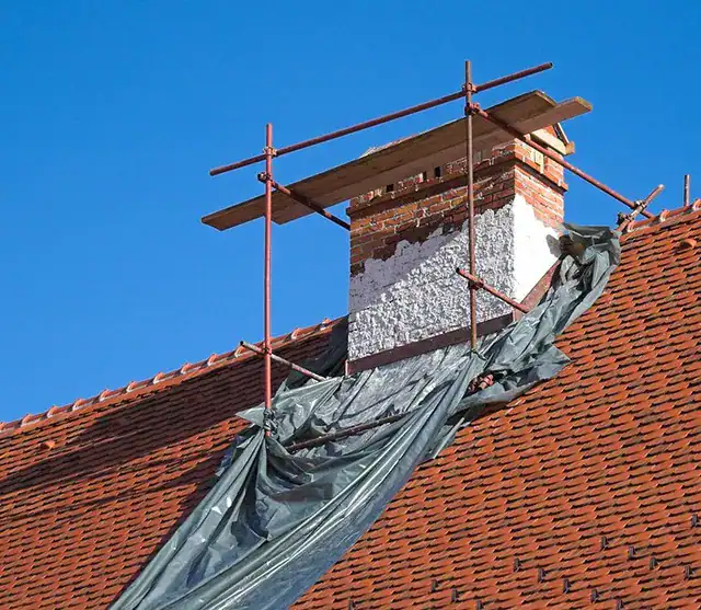 Scaffolding around brick chimney undergoing chimney repair on red tile roof in Clifton NJ