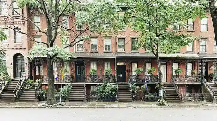 Row of brick townhouses with front stoops and iron railings; masonry work visible.