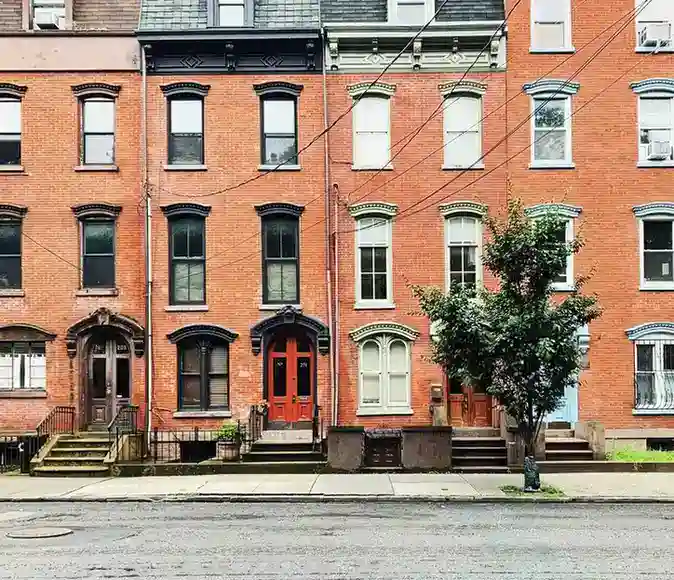 Historic brownstone row houses in downtown Jersey City, New Jersey, featuring classic red brick facades, tall windows, and traditional urban architecture.