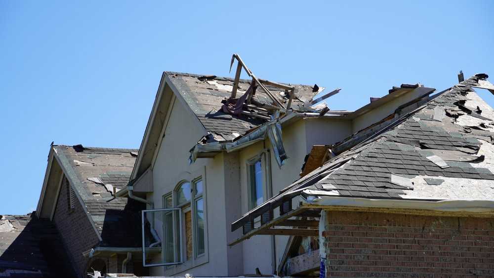 Damaged asphalt roof with missing shingles on a two-story home, emergency roofing in New Jersey