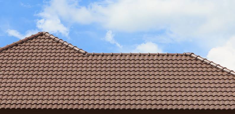 Brown clay tile roof with curved tiles under a blue sky.