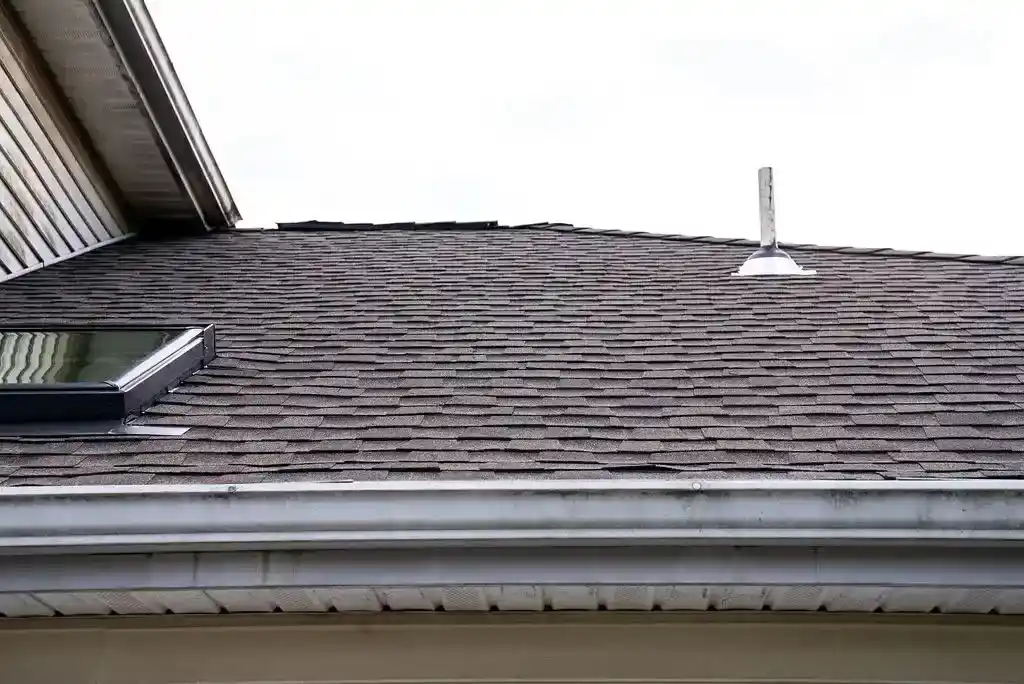 Dark asphalt shingle roof with skylight and vent on a residential home