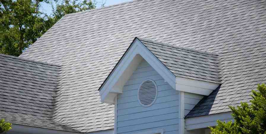 Blue siding home with gray asphalt shingle roof and round dormer vent