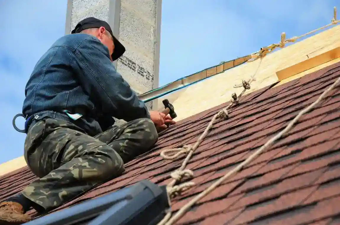 Roofer repairing storm-damaged asphalt shingle roof