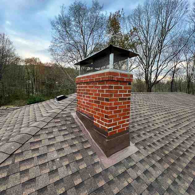 Rebuilt brick chimney with metal cap on an asphalt shingle roof