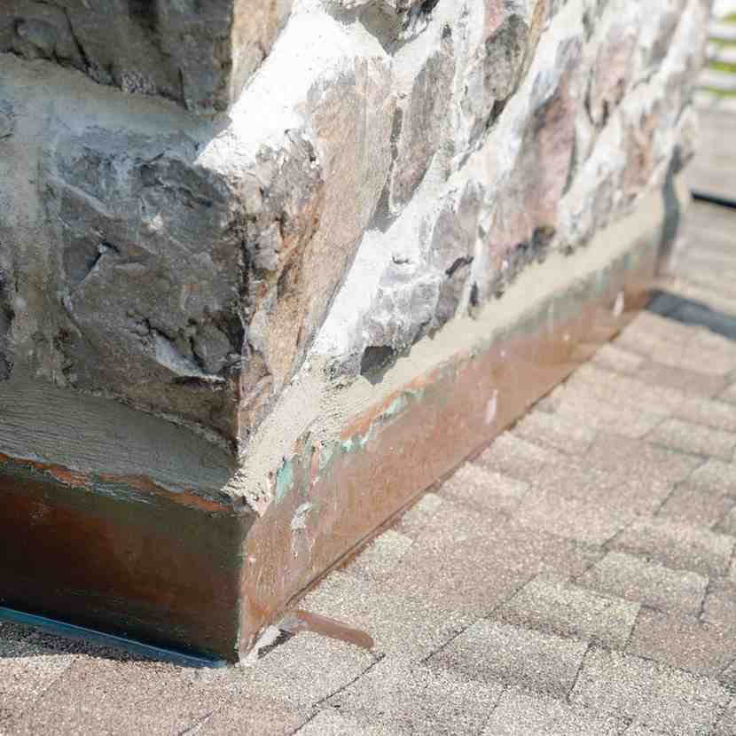 Damaged chimney masonry and flashing area on a Somerville, NJ roof showing signs of potential water intrusion.