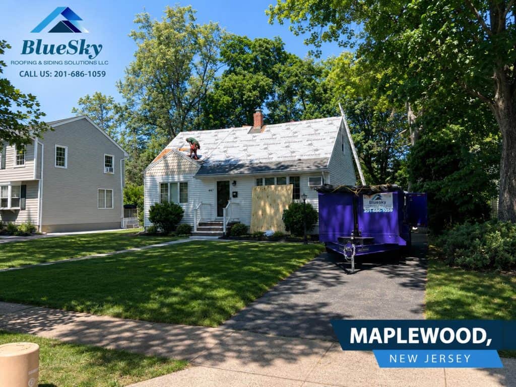 Roof replacement in Maplewood, New Jersey: worker on roof installing underlayment beside a purple trailer at a home.