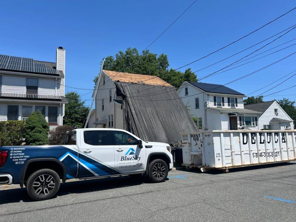 BlueSky truck beside a tarp-covered roof and dumpster during emergency roofing in New Jersey.