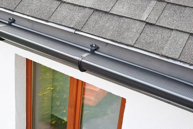 Gutter installation along a roof edge featuring a mesh guard on a New Jersey home.