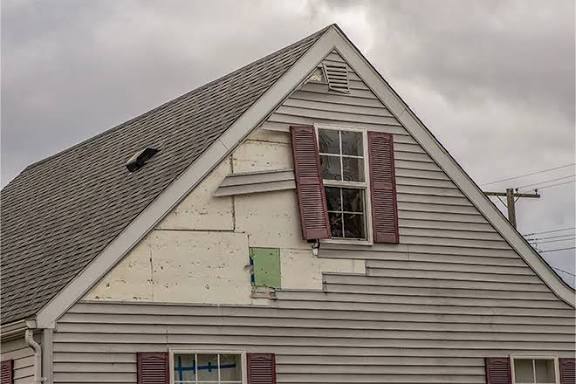Siding installation reveals exposed green sheathing on gable in New Jersey.