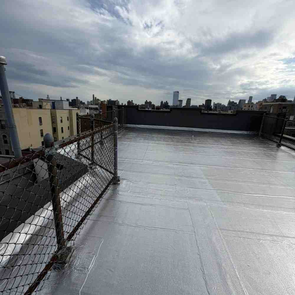 Flat rooftop with waterproof coating and city skyline in background.