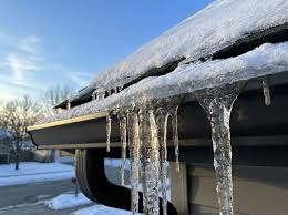 Icicles hanging from a roof edge during winter, showing ice buildup and potential roof damage